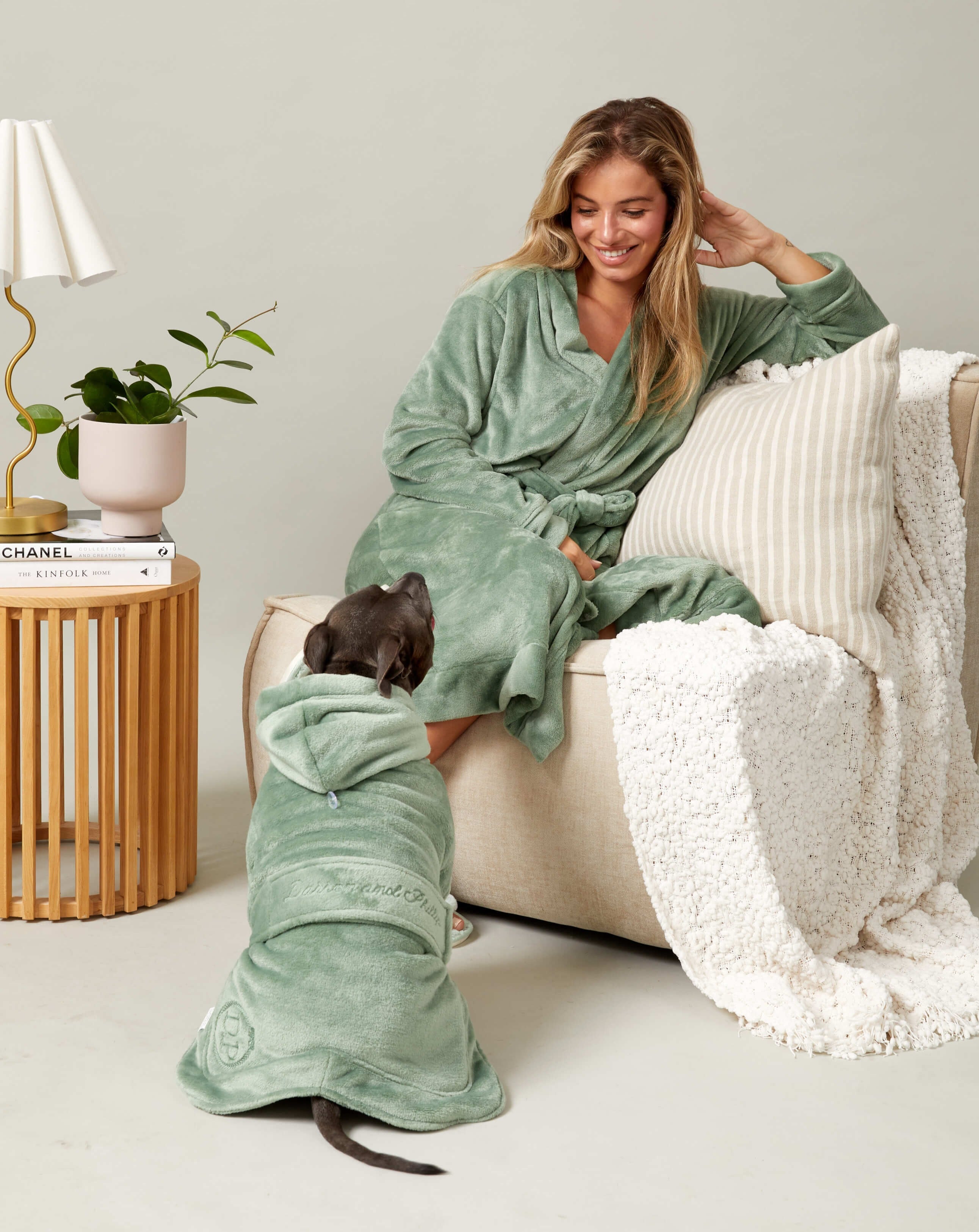 A woman and a dog wearing Darren and Phillip match your dog robes in green.