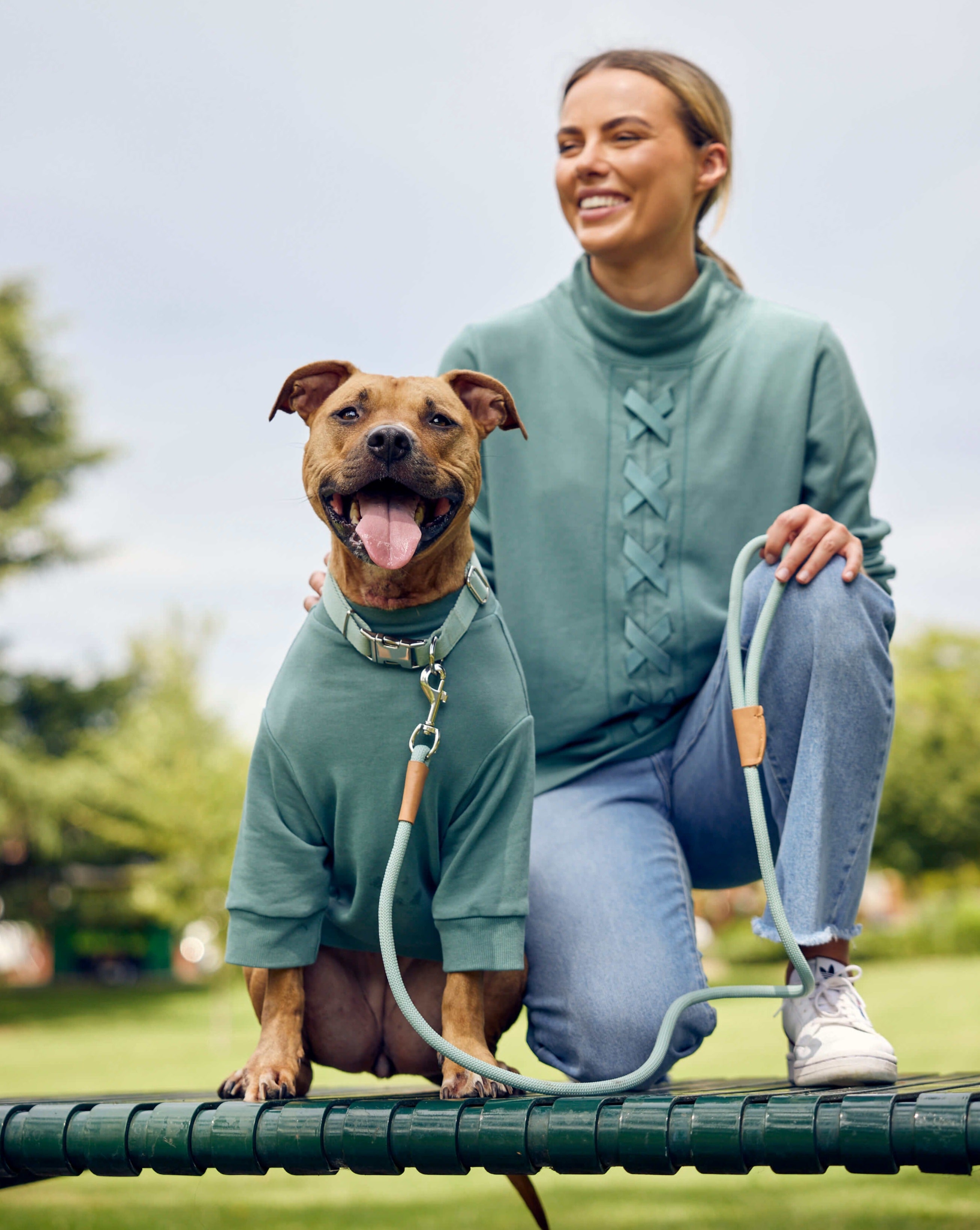 A smiling girl and her dog wearing a Darren and Phillip dog jumper.